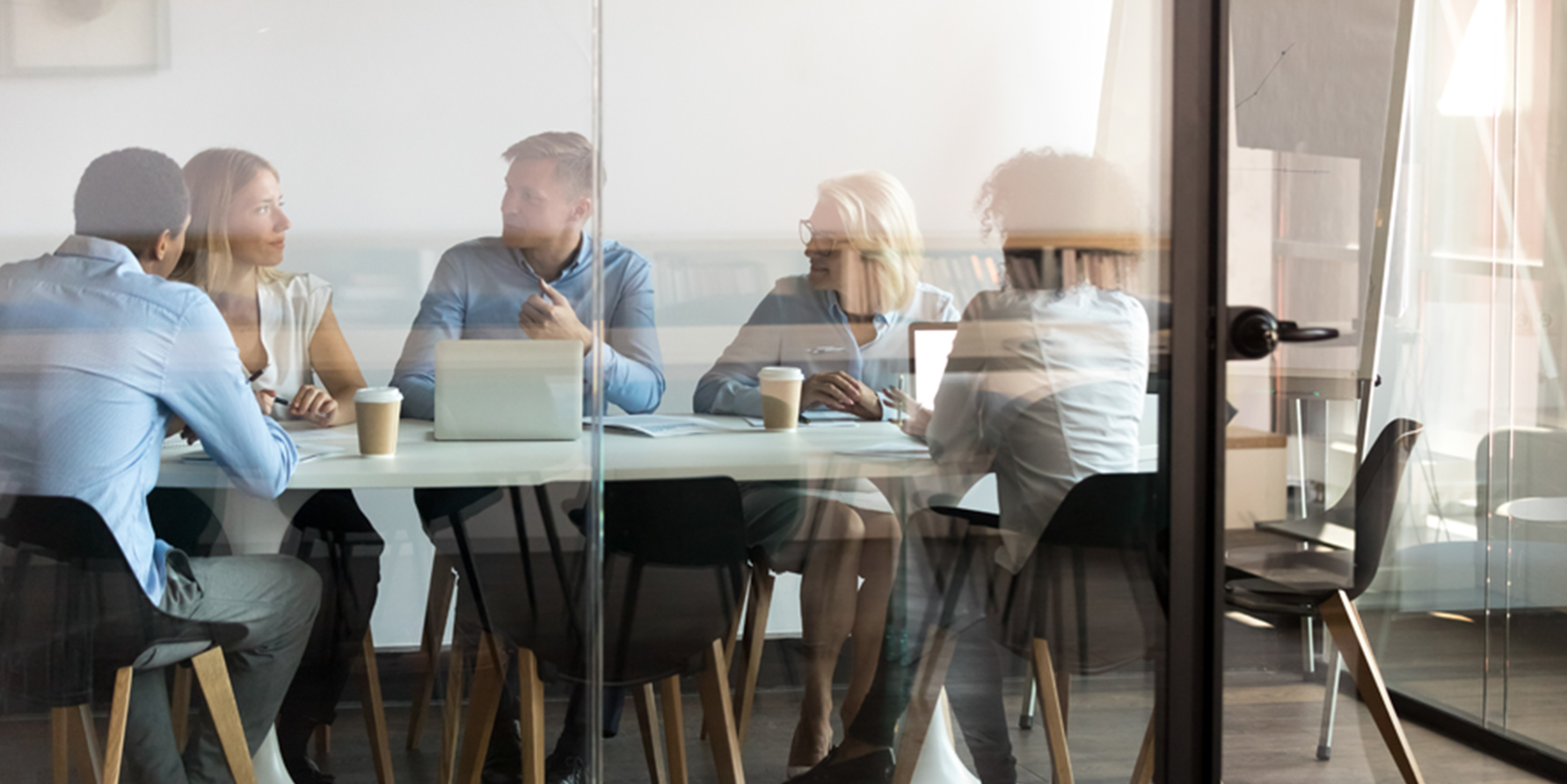 Photograph of a sales team sitting at a table in a glass conference room