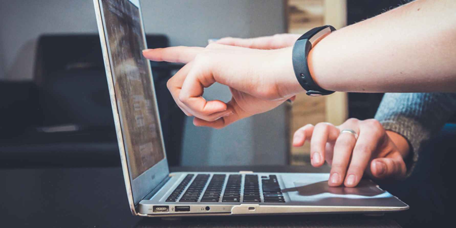 Photograph of two revenue leaders' hands pointing to a report on a laptop screen