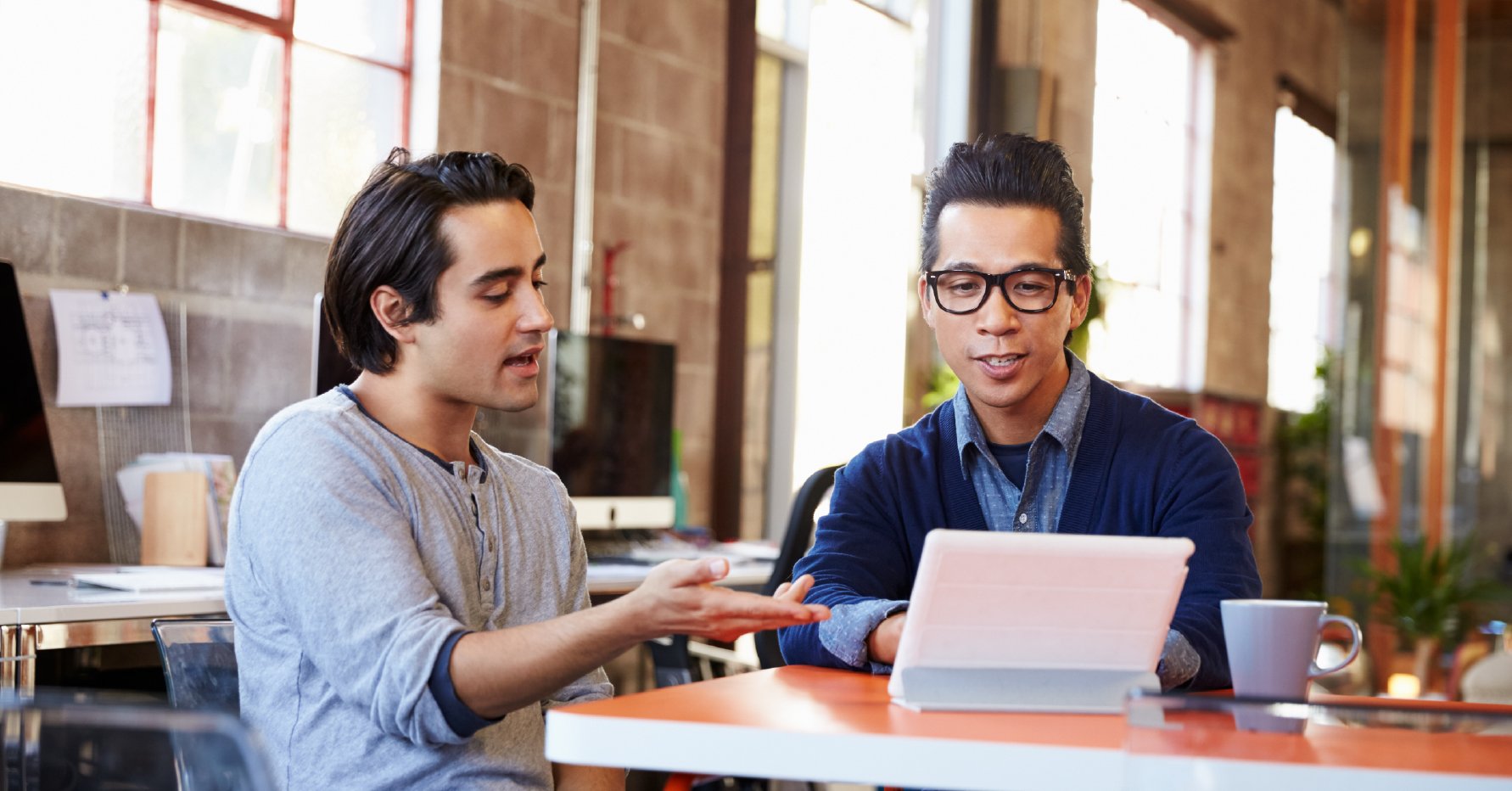 Photograph of two salespeople discussing the MEDDIC methodology in front of a tablet screen