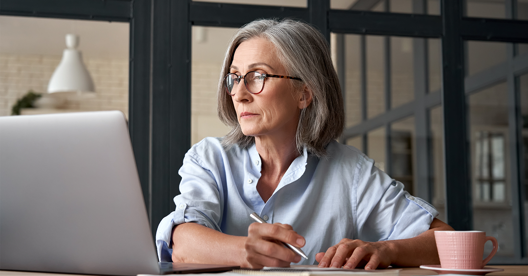 Photograph of a revenue leader writing on a report and looking at CRM data on a laptop screen