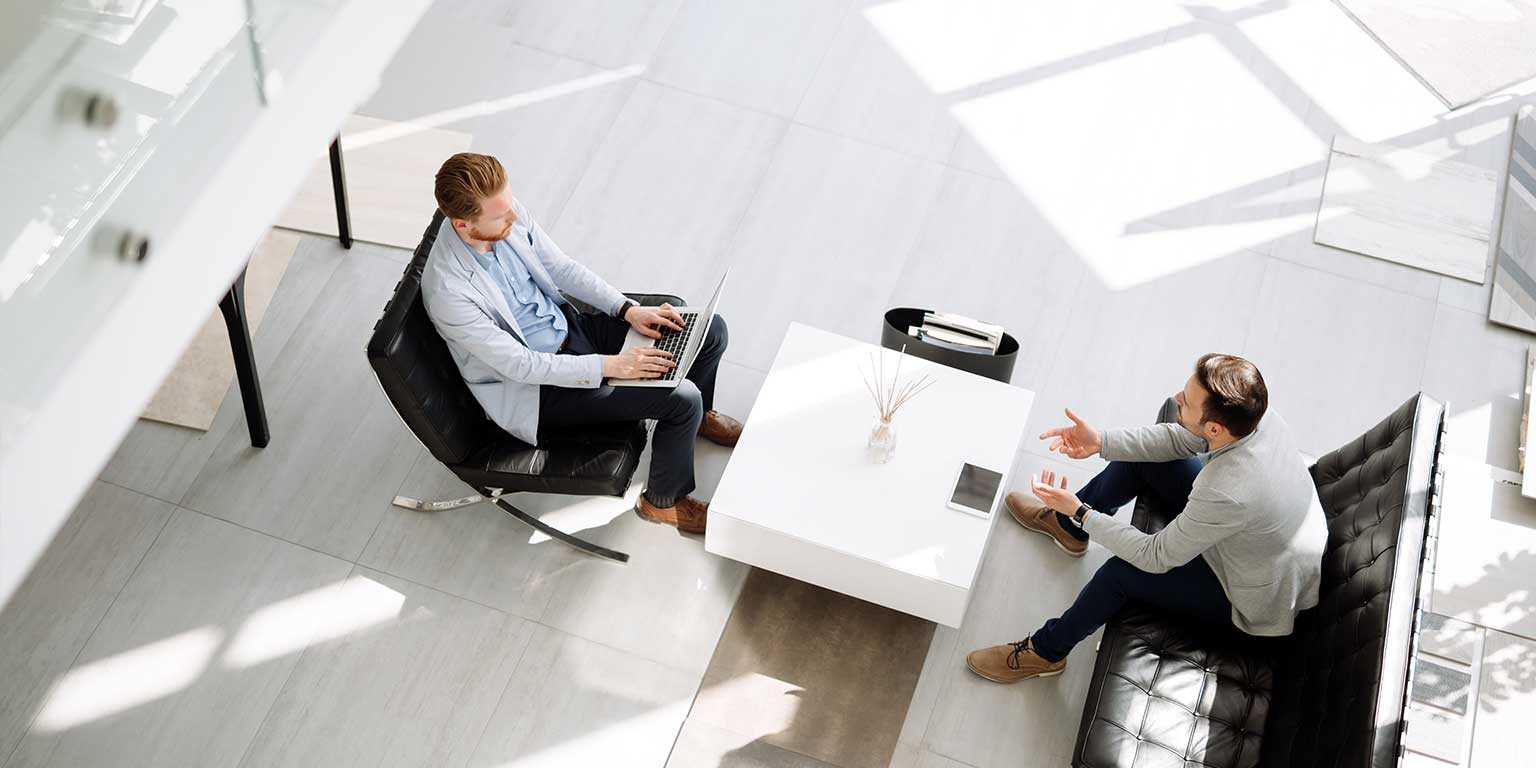 Photograph of two revenue professionals talking and typing on a laptop during a coaching session