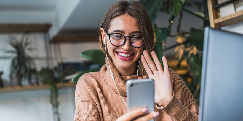 Photograph of a salesperson holding an iPhone and waving on a video call