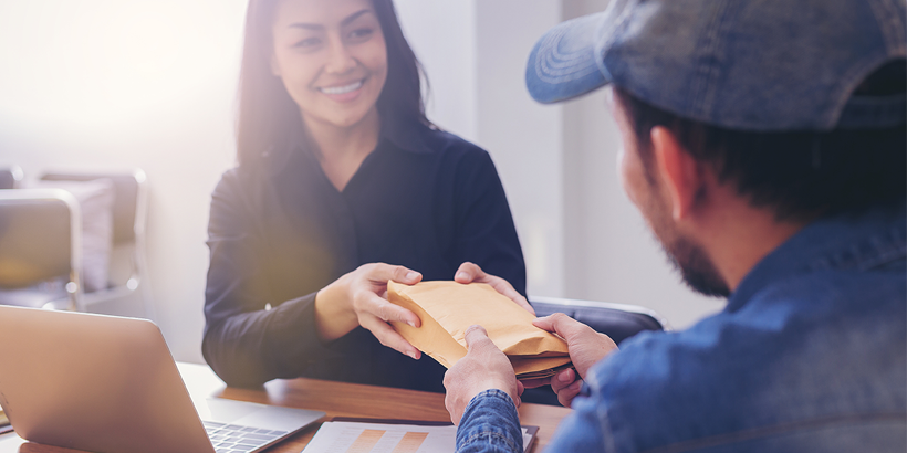 Photograph of two people closing a deal holding a package in front of a laptop and smiling