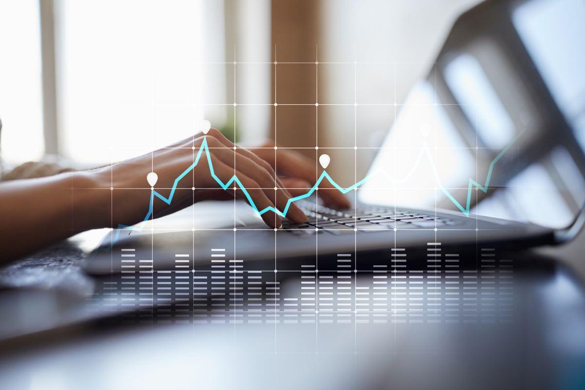 Illustration of a line graph overlapping a photograph of hands typing on a keyboard