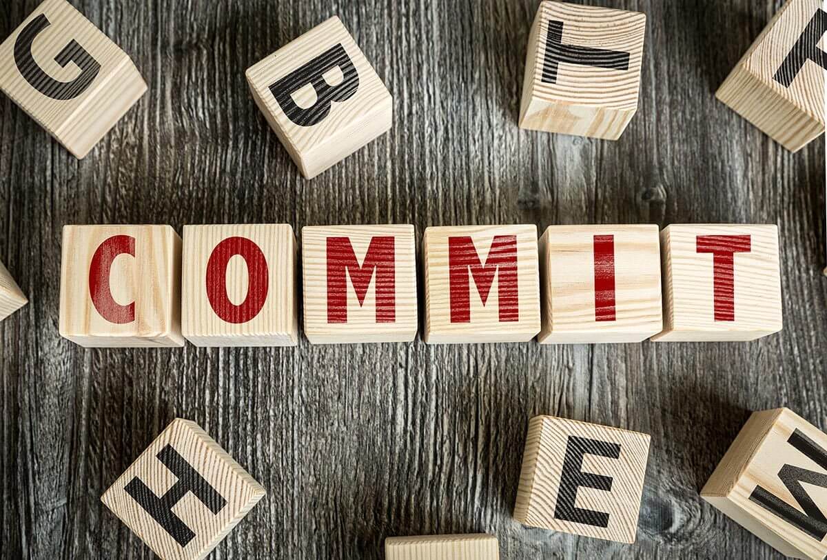 Photograph of wooden alphabet blocks spelling out COMMIT