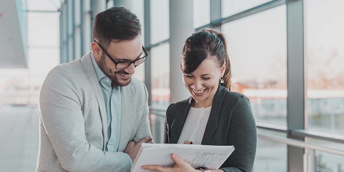 Photograph of two revenue leaders standing and reviewing a list of job titles