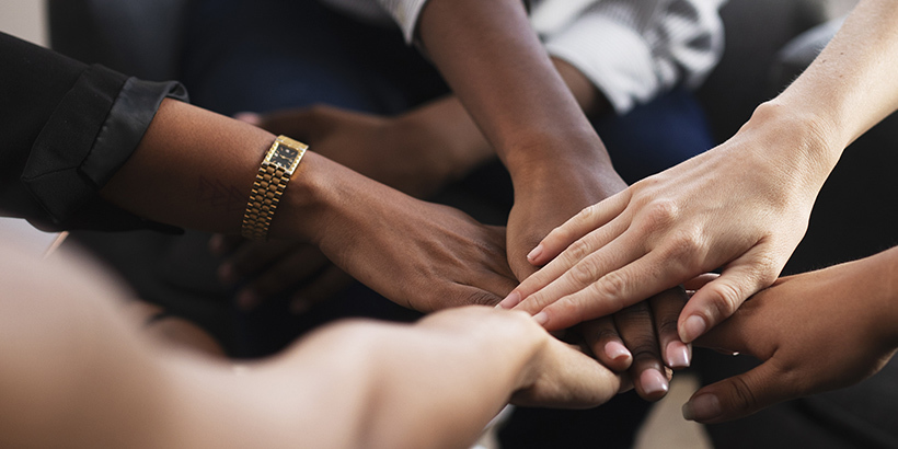 Photograph of a circle of people stacking hands