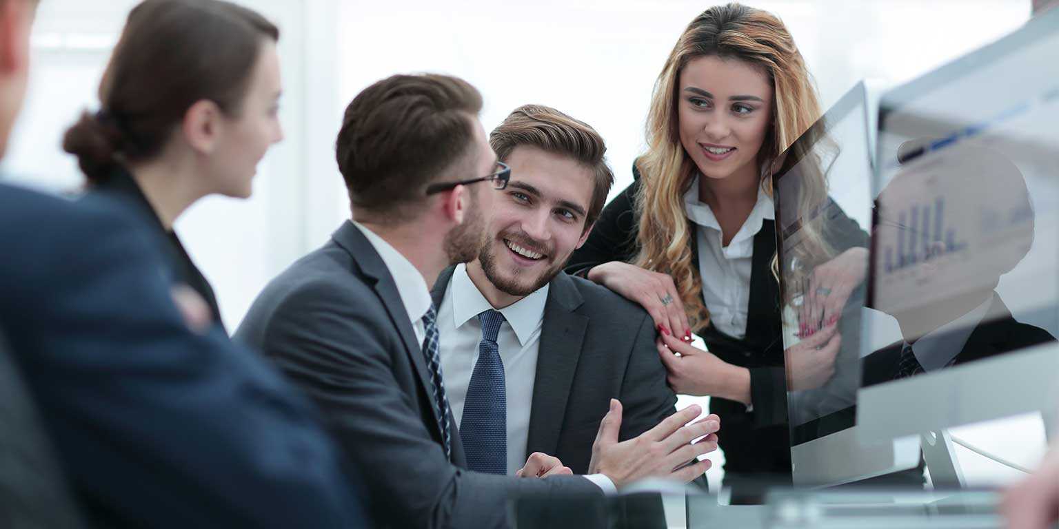 Photograph of marketing professionals discussing sales activity data in front of a computer screen