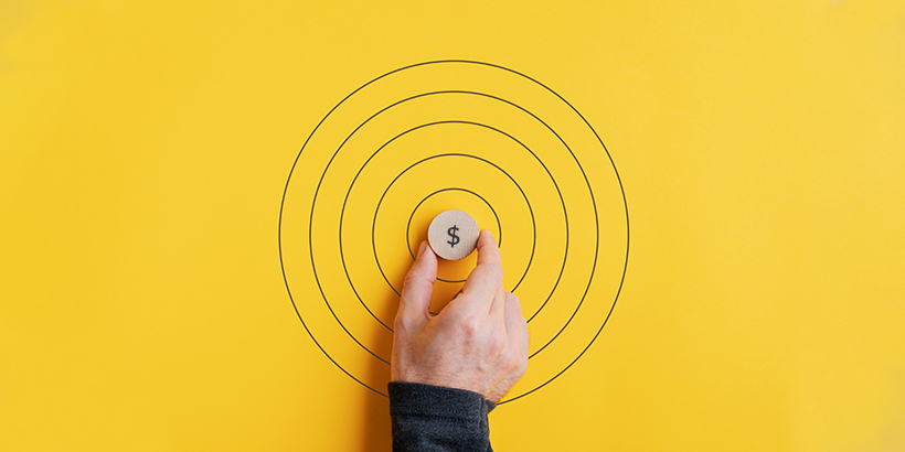 Hand placing a token labelled with a dollar sign in the middle of a bullseye