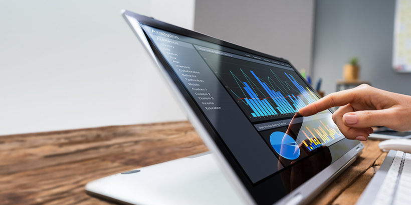 Finger touching a tablet displaying a sales performance metrics and KPIs dashboard