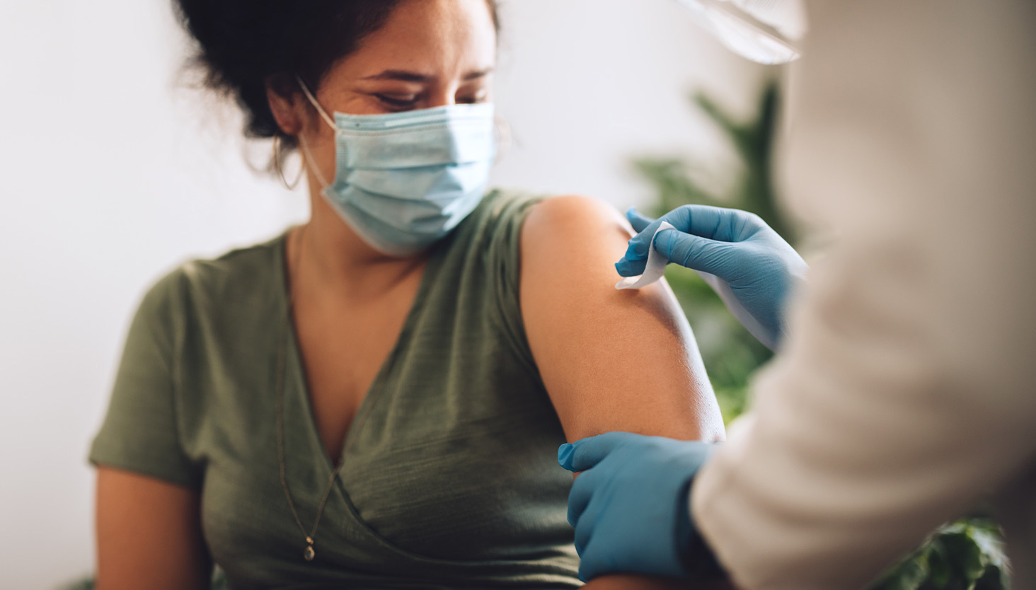 Medical professional applying a bandage to a masked person's arm