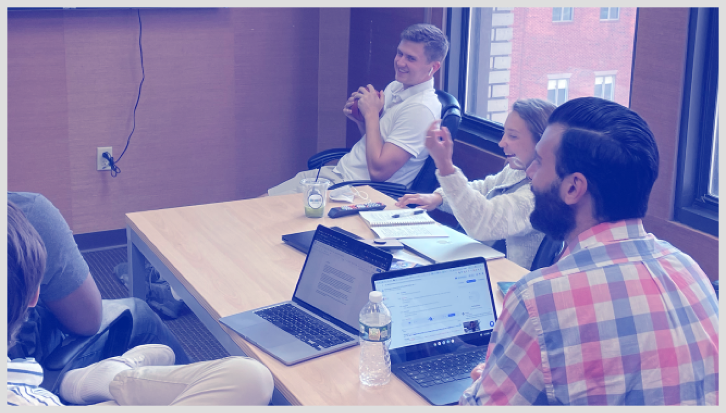 Smiling people in a meeting room with laptops