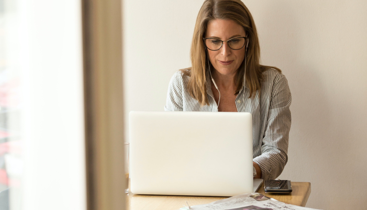 Photograph of a businessperson typing on a laptop with headphones